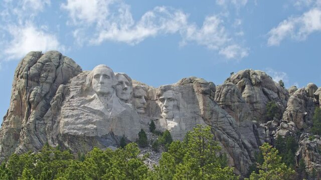Looking past pine trees towards Mount Rushmore as clouds move overhead during timelapse in the Black Hills South Dakota.