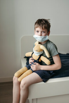 A little boy with a toy in a protective medical mask.