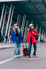 Obraz premium Two happy girls walking near airport, with luggage. Air travel, summer holiday