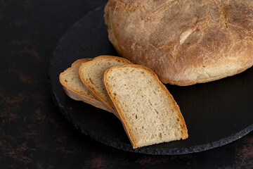 Organic round bread on a dark wooden background. Sliced bread. Traditional sourdough bread