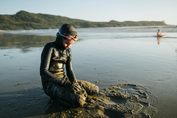 Naklejka premium Girl in wetsuit covered in sand
