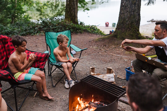 Roasting marshmallow on campsite in bathing suit