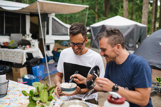 Two men enjoying making dinner on campsite