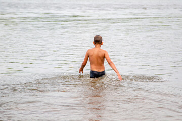kid enters the water while swimming on the beach