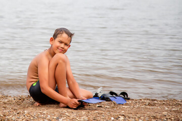 boy on the shore puts on diving fins © vitec40