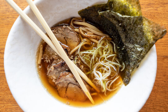 Close up of a pork ramen soup over a wood table