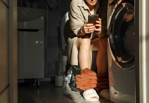 Crop female browsing smartphone on toilet