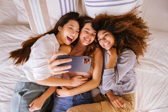 Happy women taking selfie on bed