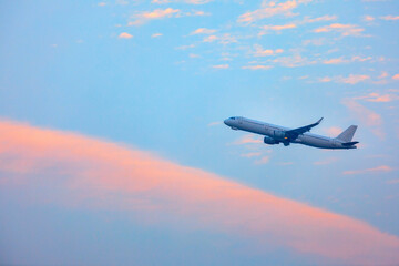 Front view of commercial airplane flying over sunset cloud and sky