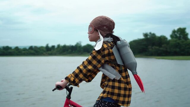 Asian kid with jet pack riding bike. Child girl playing at outdoor
