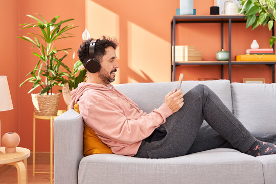 Male in headphones chilling on sofa with tablet