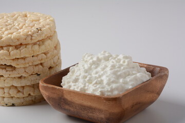 Natural cottage cheese in a bowl  and Puffed rice bread on a white background