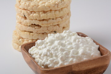 Natural cottage cheese in a bowl  and Puffed rice bread on a white background