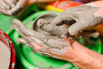 A close-up of a potter's hand creates a clay bowl on a potter's wheel. pottery training