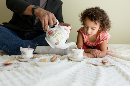 Girl carefully watches father refill her cup