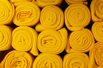 Twisted yellow blankets in a roll as background, home textile