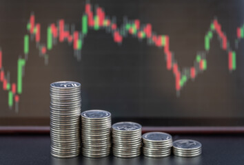 Business Money and Investment and Planning Concept. Closeup of stack of silver coins with candlestick chart as background.