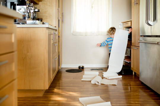 Laughing toddler unrolls paper towels