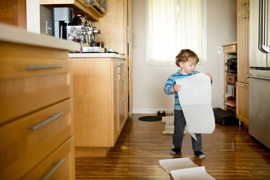 Toddler plays with paper towels in kitchen