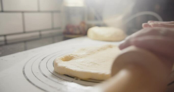 Slow motion Close up hands of bakery Chef preparing kneading roll out dough with a rolling pin on the table, Ingredients and preparation stages for cooking making bread cake at kitchen