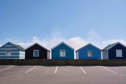 Waves crashing spray above Beach huts. Southwold, Suffolk, UK.
