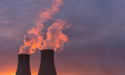 Nuclear power plant against sky at sunset