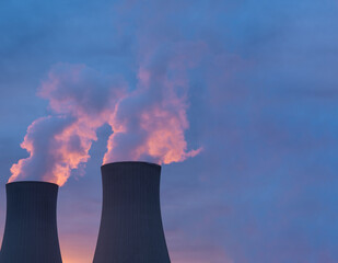 Nuclear power plant against sky at sunset