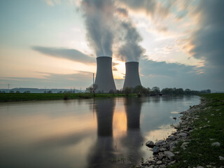 Obraz na płótnie Canvas Nuclear power plant against sky by the river at sunset
