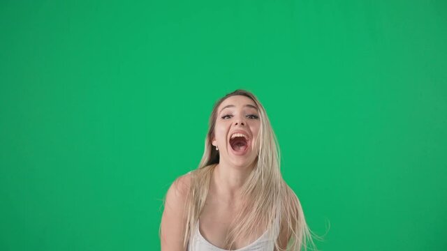 luck and success, emotional happy young woman rejoices in victory shows with hands yes jumps and turns her head on a green screen, chrome key