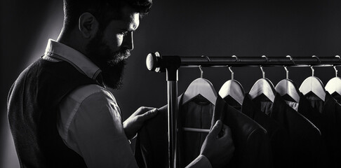 Male suits hanging in a row. Men clothing, boutiques. Tailor, tailoring. Stylish men's suit. Man...