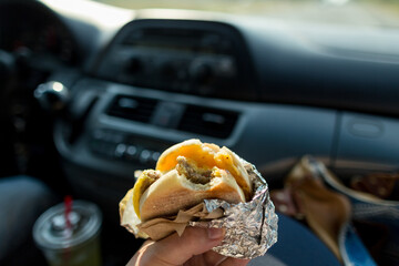 Passenger eats breakfast sandwich in vehicle