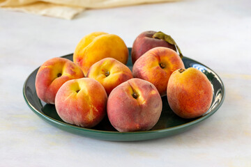 Fototapeta na wymiar Ripe fresh peaches on green ceramic plate