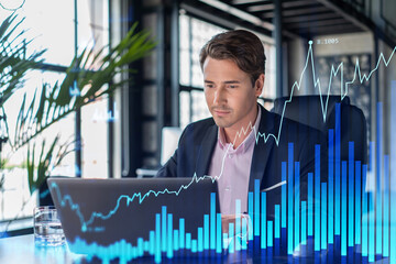 Handsome businessman in suit at workplace working with laptop to optimize trading strategy at...