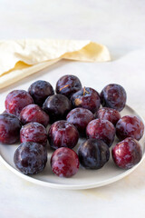 Ripe fresh damsons on a white ceramic plate