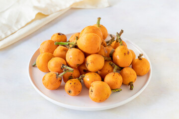 Ripe fresh loquat (Eriobotrya japonica) on a white ceramic plate