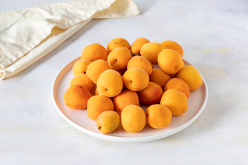 Ripe fresh apricots on a white ceramic plate