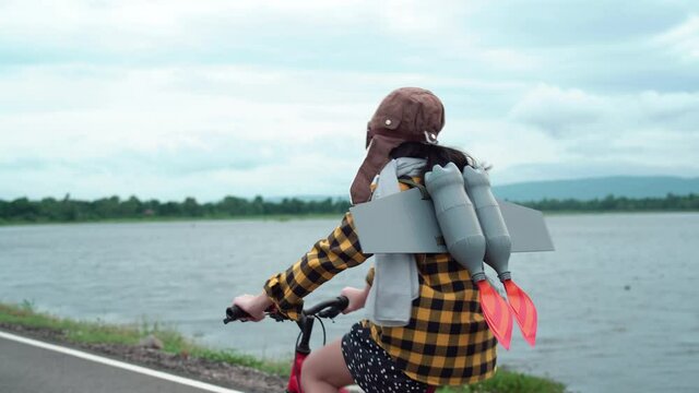 Asian kid with jet pack riding bike. Child girl playing at outdoor