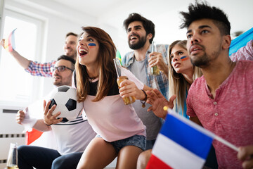 Obraz premium Happy group of young friends watching television and supporting their team