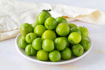 Ripe fresh green plums on a white ceramic plate