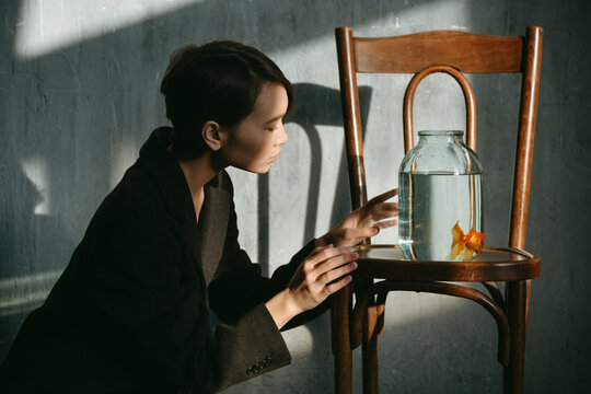 Asian girl with an aquarium fish in a dark room.