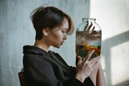Asian girl with an aquarium fish in a dark room.