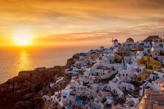 Golden summer sunset behind the picturesque village of Oia, at the edge of the cadera at Santorini island, Cyclades, Greece