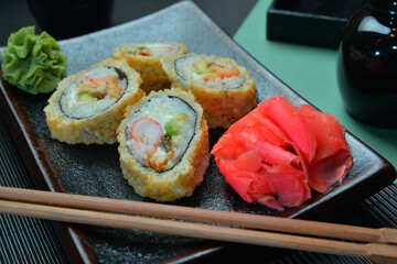 Sushi roll with salmon and shrimp tempura on dark plate