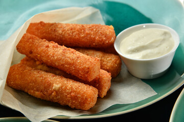 Breaded mozzarella cheese sticks with sauce closeup