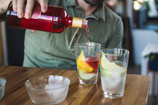 Man serving a drink, a red gin tonic