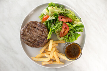 Grilled beef steak with French Fries vegetables tomatoes and sauce on top view