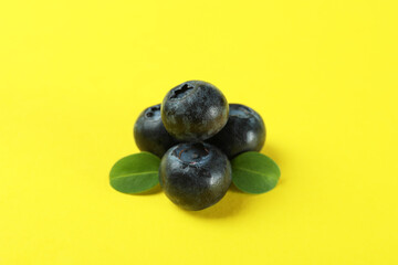Fresh blueberry with leaves on yellow background