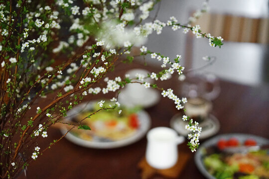 Close-up of flowers on the table with homemade dinner in the background