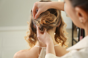 Stylist working with client in salon, making hairstyle