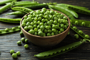 Bowl with fresh pea seeds on wooden background
